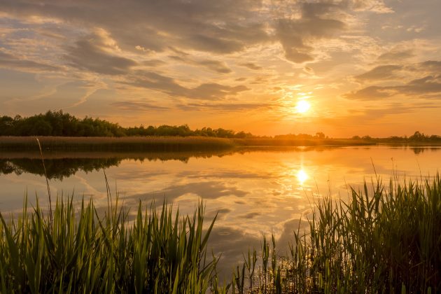 A beautiful orange, red, and yellow sunset above a vast lake.