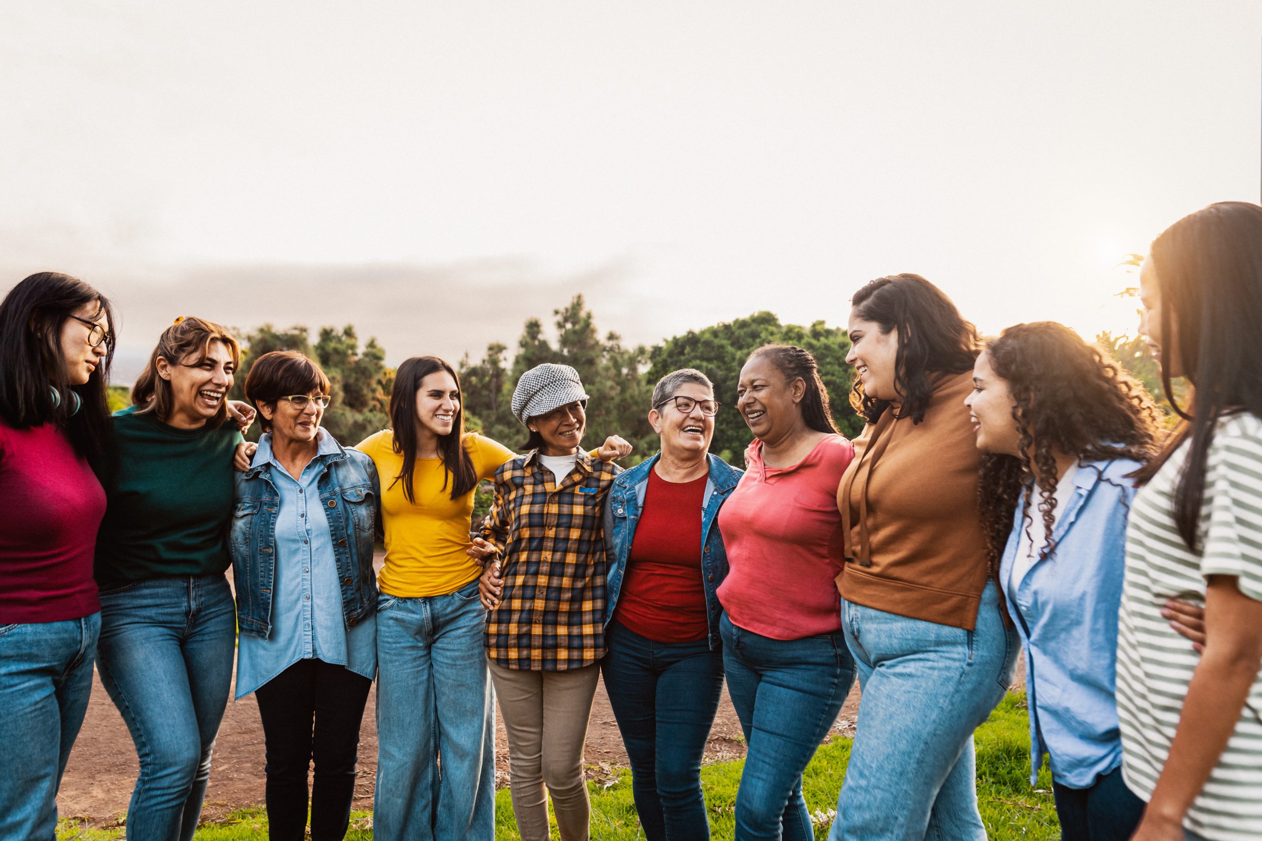 Happy multigenerational group of women with different ages and ethnicities having fun in a public park -