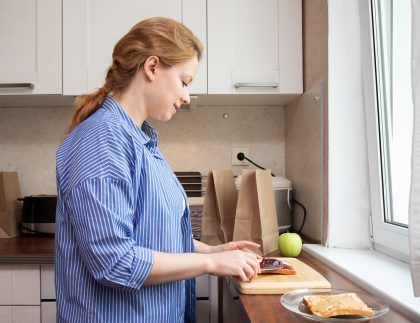 Children of alcoholics week; a mom making a peanut butter and jelly sandwich for her child's school lunch.