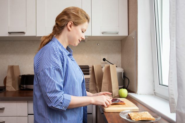 Children of alcoholics week; a mom making a peanut butter and jelly sandwich for her child's school lunch.